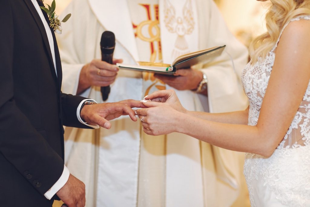 Bride placing ring on groom's finger during ceremony.
