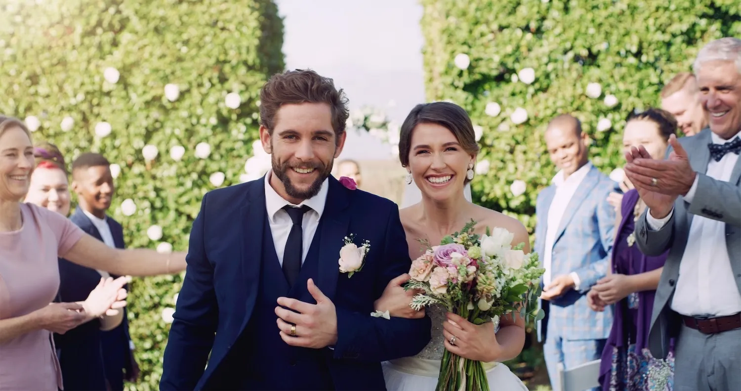 Smiling couple walking down aisle at outdoor wedding