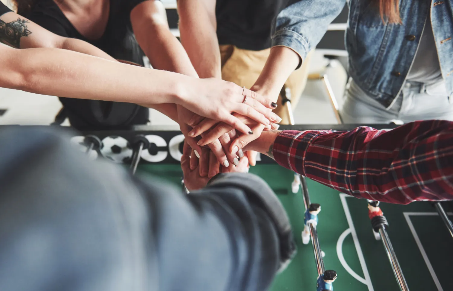 Team hands joined over foosball table