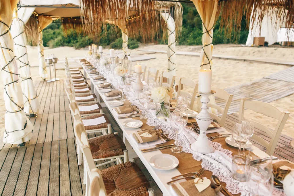 Elegant beachside wedding reception table under thatched canopy