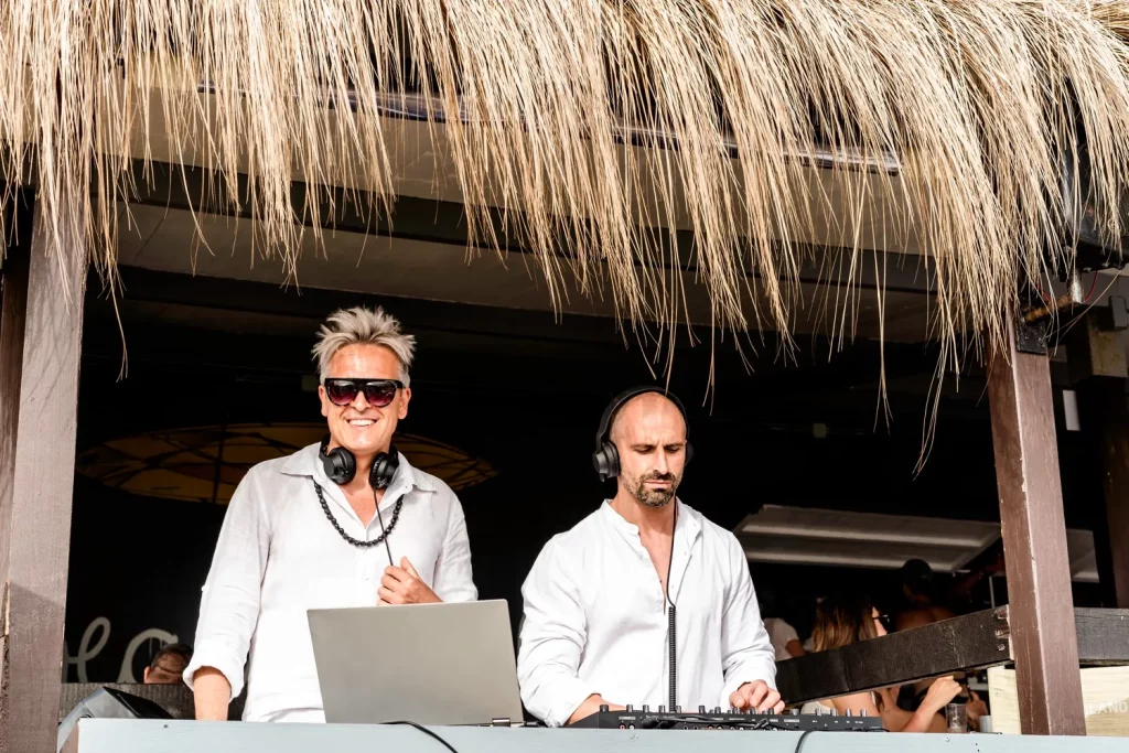 Two DJs performing at a beachside bar