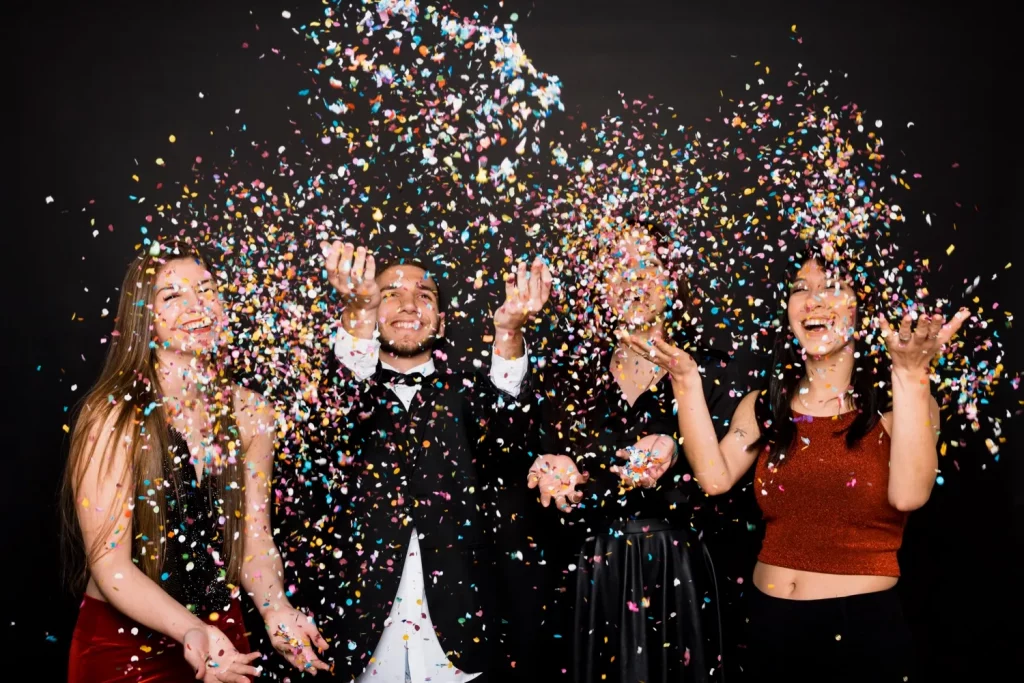 Four friends throwing colorful confetti at party
