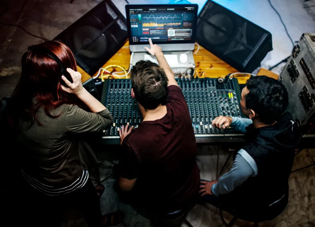 Three people working at audio mixing console