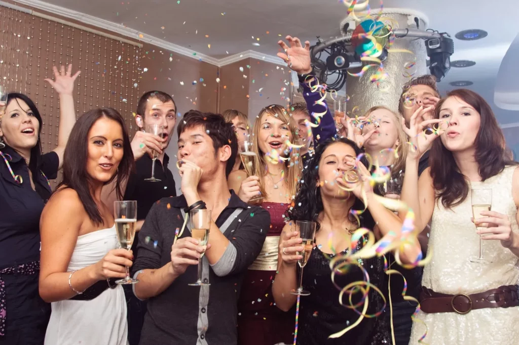 Friends celebrating with champagne and confetti indoors