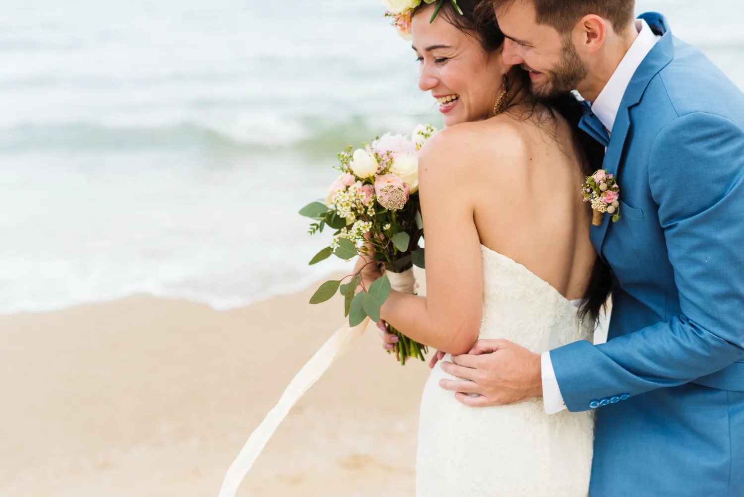 Bride and groom embracing on beach wedding day