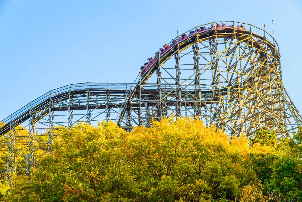 Wooden roller coaster over autumn trees